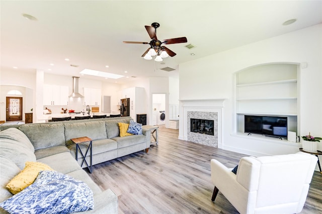 12006 Bright Landing Ct, Pearland, TX 77584 - living room with a ceiling fan, light wood-style flooring, a glass covered fireplace, built in shelves, and recessed lighting
