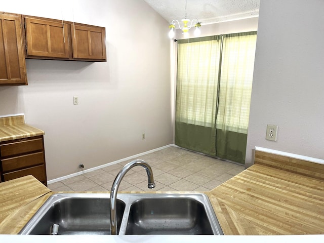 21007 Rivershadows Ln, Spring, TX 77388 - kitchen featuring a sink, light tile patterned floors, light countertops, and brown cabinetry