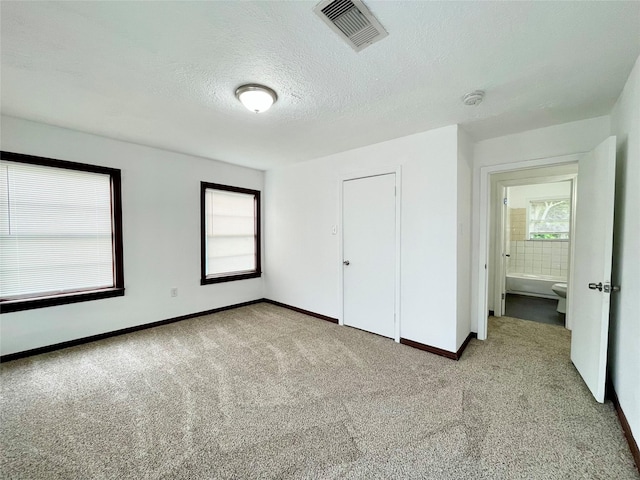6802 Crestridge St, Houston, TX 77033 - unfurnished bedroom with light colored carpet, multiple windows, baseboards, a textured ceiling, and a closet
