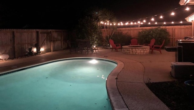 37 N Erik Dr, Angleton, TX 77515 - pool at night featuring a patio, an outdoor fire pit, and a fenced backyard
