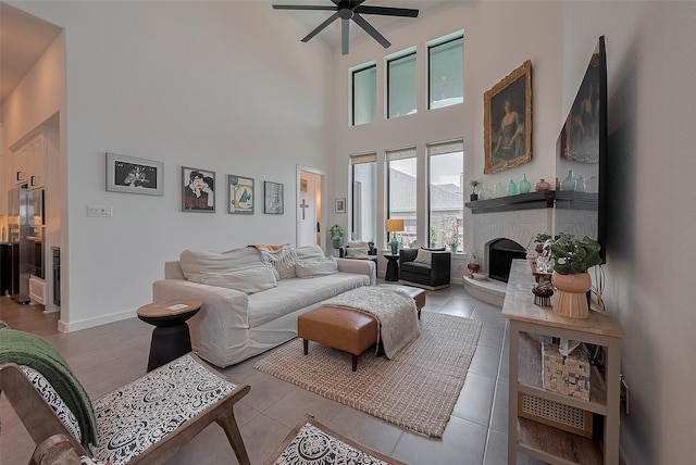 29118 Sage Trace Ct, Fulshear, TX 77441 - living room featuring a ceiling fan, a towering ceiling, a brick fireplace, tile patterned flooring, and baseboards