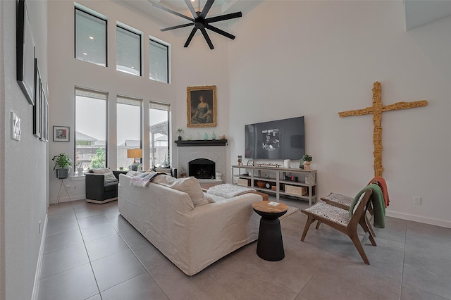 29118 Sage Trace Ct, Fulshear, TX 77441 - living area with a towering ceiling, baseboards, tile patterned flooring, a brick fireplace, and a ceiling fan