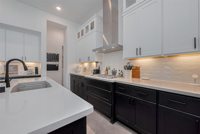 29118 Sage Trace Ct, Fulshear, TX 77441 - kitchen featuring a sink, wall chimney range hood, dark cabinetry, stainless steel gas stovetop, and light countertops