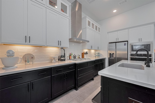 29118 Sage Trace Ct, Fulshear, TX 77441 - kitchen with wall chimney range hood, stainless steel appliances, dark cabinets, a sink, and light countertops