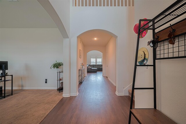 308 Morning Dove Trl, Sealy, TX 77474 - corridor with dark wood-style floors, arched walkways, baseboards, and a towering ceiling