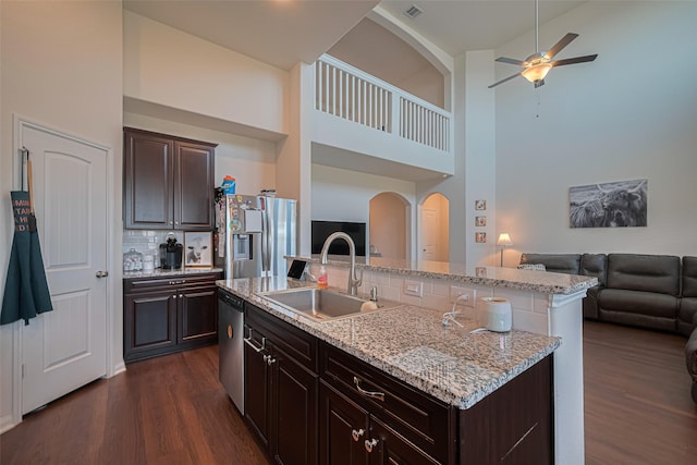 308 Morning Dove Trl, Sealy, TX 77474 - kitchen featuring a sink, stainless steel appliances, open floor plan, arched walkways, and dark wood-style floors