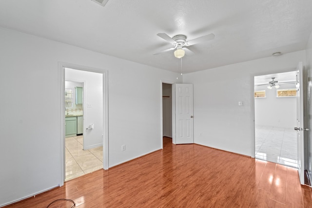 13911 Fraser Lake Ln, Houston, TX 77083 - unfurnished bedroom with light wood finished floors, a walk in closet, connected bathroom, ceiling fan, and baseboards