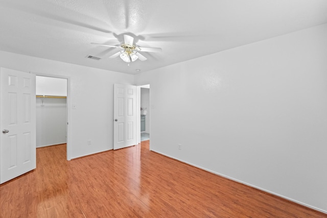 13911 Fraser Lake Ln, Houston, TX 77083 - unfurnished bedroom with light wood-type flooring, a spacious closet, a closet, a ceiling fan, and baseboards