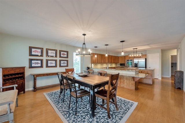 1327 Tiki Dr, Tiki Island, TX 77554 - dining room featuring light wood-type flooring, a chandelier, and baseboards