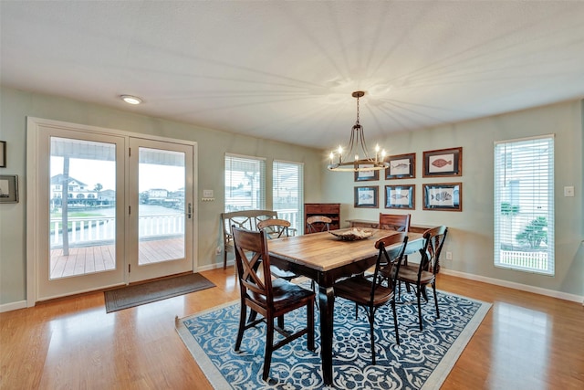 1327 Tiki Dr, Tiki Island, TX 77554 - dining room with a chandelier, light wood-type flooring, baseboards, and plenty of natural light