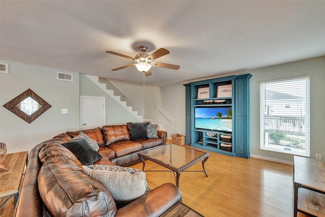 1327 Tiki Dr, Tiki Island, TX 77554 - living room with stairway, a ceiling fan, and light wood-style flooring