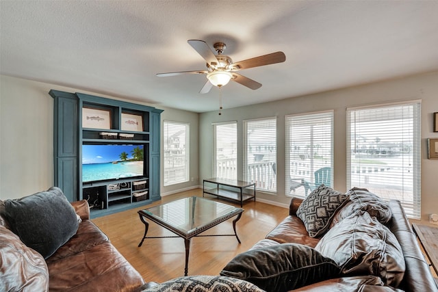 1327 Tiki Dr, Tiki Island, TX 77554 - living room with a ceiling fan, light wood-style flooring, baseboards, and a textured ceiling