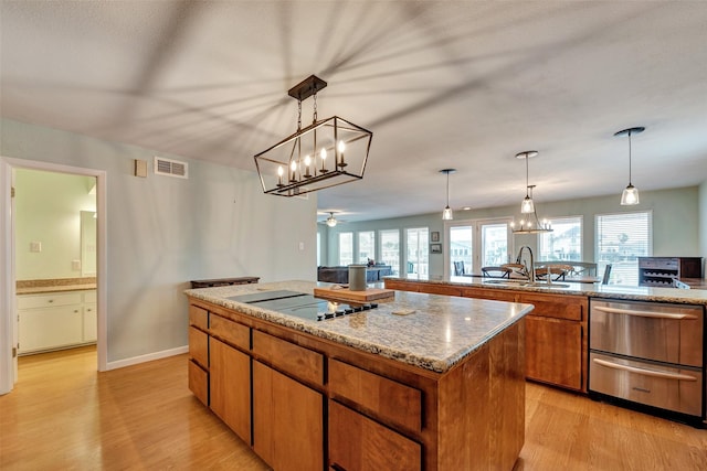 1327 Tiki Dr, Tiki Island, TX 77554 - kitchen with a center island, a sink, black electric stovetop, light wood-style flooring, and brown cabinetry