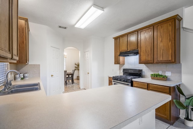 3102 Spring Flower Ln, Spring, TX 77388 - kitchen with gas range oven, under cabinet range hood, arched walkways, a sink, and light tile patterned flooring