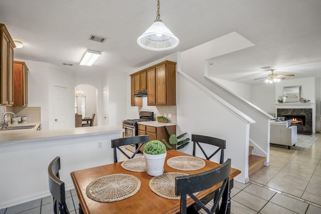 3102 Spring Flower Ln, Spring, TX 77388 - dining space featuring arched walkways, light tile patterned flooring, stairway, a ceiling fan, and a premium fireplace