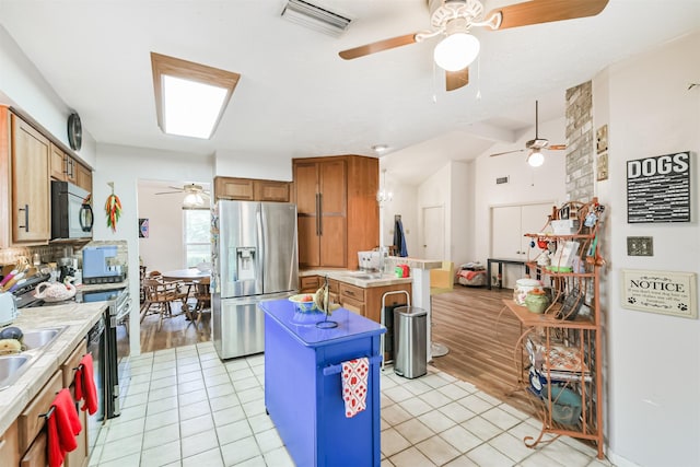 12206 Tawakom Dr, Tomball, TX 77375 - kitchen with stainless steel fridge with ice dispenser, ceiling fan, black microwave, a kitchen island, and light countertops