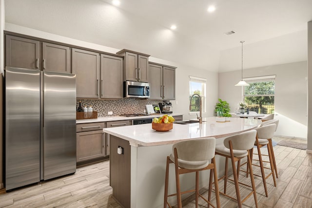 24743 Levante Dr, Richmond, TX 77406 - kitchen with stainless steel appliances, light wood-style flooring, lofted ceiling, light countertops, and a sink