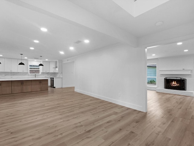 9414 Stockport Dr, Spring, TX 77379 - unfurnished living room with recessed lighting, light wood-style flooring, baseboards, and a brick fireplace