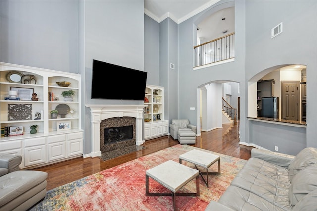 22719 Arbor Stream Dr, Katy, TX 77450 - living room with wood finished floors, arched walkways, crown molding, a towering ceiling, and a high end fireplace