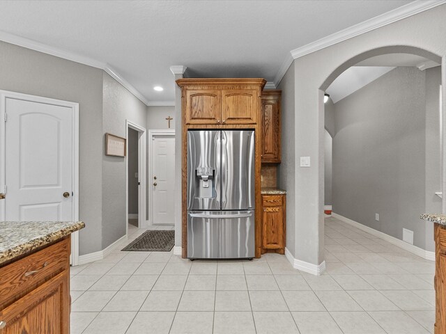 12008 7th St, Santa Fe, TX 77510 - kitchen with stainless steel fridge with ice dispenser, arched walkways, ornamental molding, light stone countertops, and light tile patterned floors