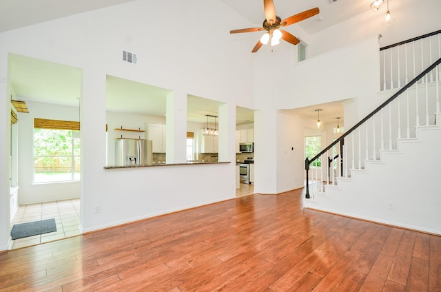 7919 Clarion Way, Houston, TX 77040 - unfurnished living room with stairs, light wood finished floors, high vaulted ceiling, ceiling fan, and healthy amount of natural light