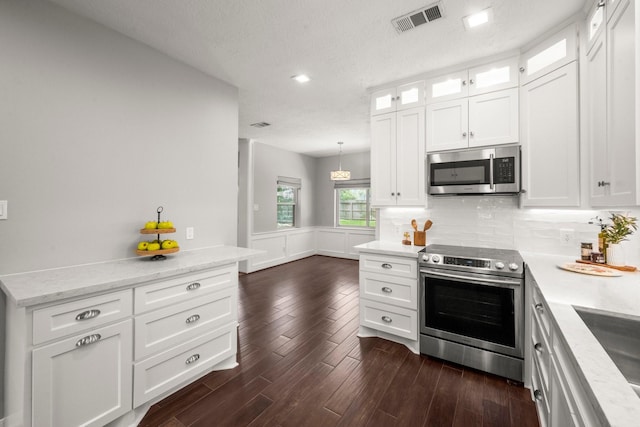 16907 Misty Creek Dr, Spring, TX 77379 - kitchen featuring appliances with stainless steel finishes, white cabinetry, glass insert cabinets, backsplash, and dark wood finished floors
