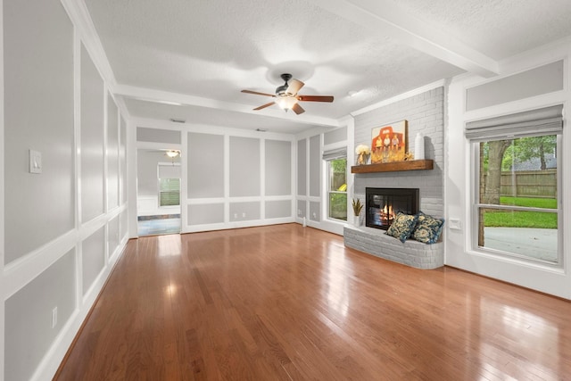 16907 Misty Creek Dr, Spring, TX 77379 - unfurnished living room featuring a ceiling fan, a brick fireplace, plenty of natural light, wood finished floors, and a textured ceiling