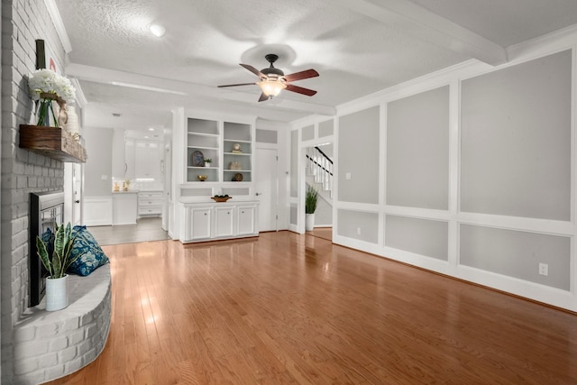 16907 Misty Creek Dr, Spring, TX 77379 - unfurnished living room featuring a fireplace, ceiling fan, light wood-style floors, stairway, and a textured ceiling