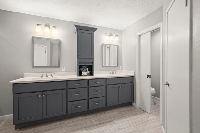 16907 Misty Creek Dr, Spring, TX 77379 - bathroom featuring double vanity, toilet, a textured ceiling, and baseboards