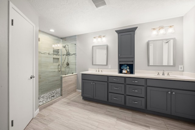 16907 Misty Creek Dr, Spring, TX 77379 - bathroom with a stall shower, double vanity, a textured ceiling, and baseboards