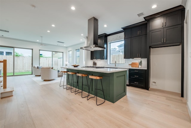 1724 Ridgewood St, Houston, TX 77006 - kitchen featuring island exhaust hood, light wood-type flooring, light countertops, a breakfast bar area, and open floor plan