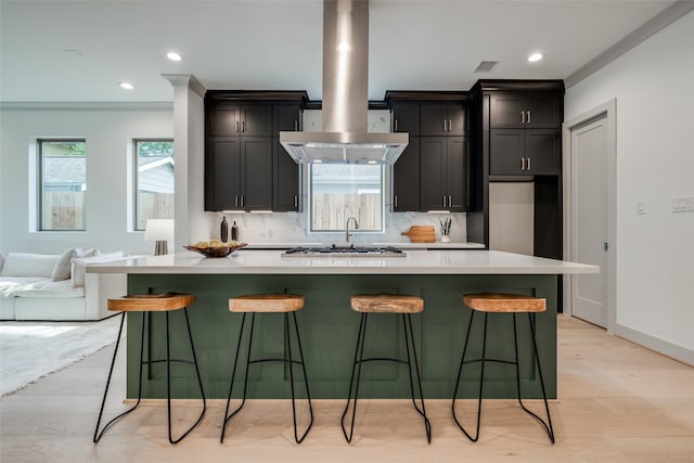 1724 Ridgewood St, Houston, TX 77006 - kitchen featuring light countertops, island exhaust hood, a spacious island, a kitchen breakfast bar, and light wood finished floors