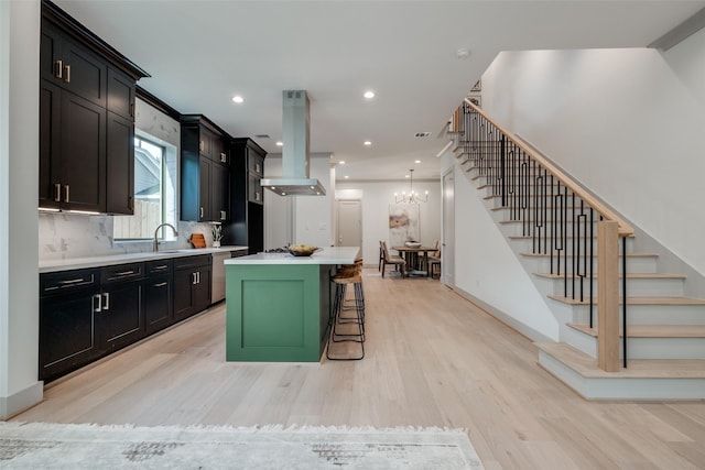 1724 Ridgewood St, Houston, TX 77006 - kitchen featuring island range hood, dark cabinetry, light wood-style flooring, a center island, and light countertops