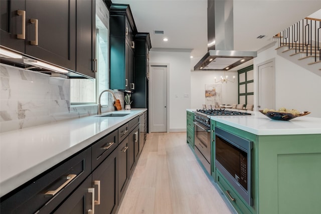 1724 Ridgewood St, Houston, TX 77006 - kitchen with island range hood, stainless steel appliances, a sink, backsplash, and light wood-style floors