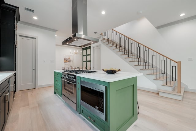 1724 Ridgewood St, Houston, TX 77006 - kitchen with green cabinetry, island range hood, gas range oven, light wood-type flooring, and recessed lighting