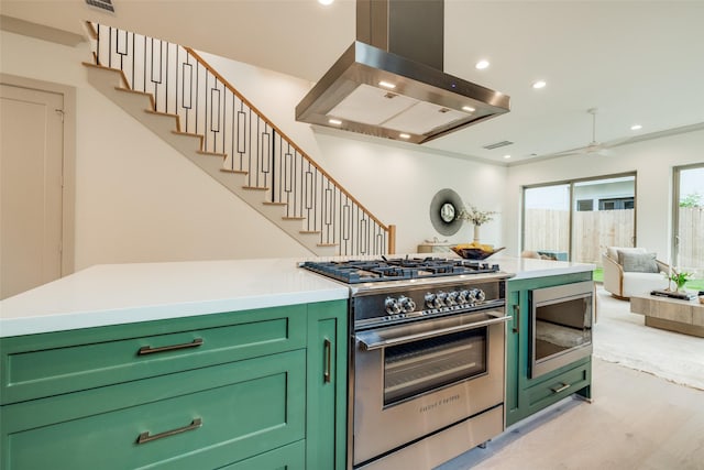 1724 Ridgewood St, Houston, TX 77006 - kitchen with green cabinetry, appliances with stainless steel finishes, wall chimney range hood, light wood finished floors, and light countertops