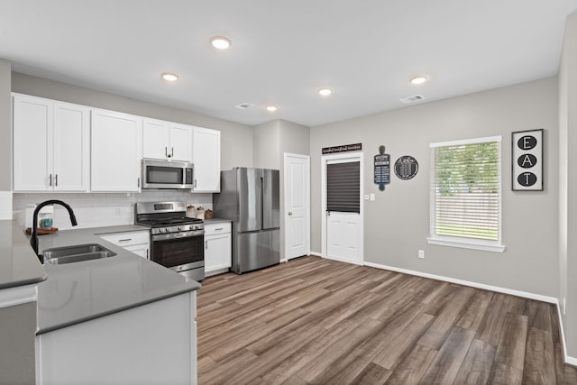 7315 Parkview Dr, Hitchcock, TX 77563 - kitchen with stainless steel appliances, a sink, wood finished floors, decorative backsplash, and white cabinetry