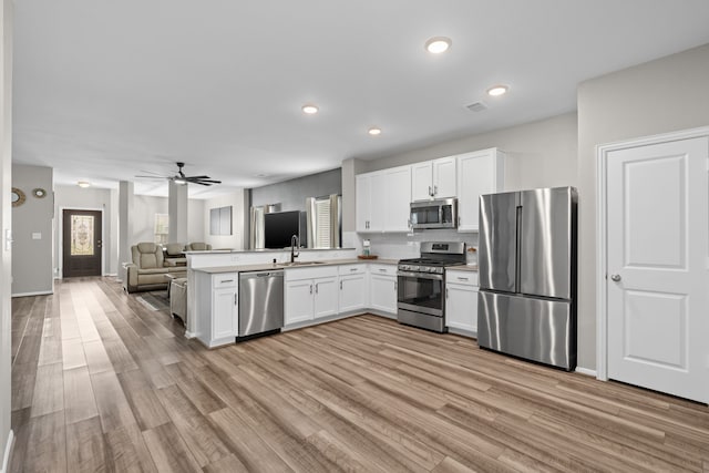 7315 Parkview Dr, Hitchcock, TX 77563 - kitchen featuring appliances with stainless steel finishes, open floor plan, a sink, a peninsula, and white cabinets