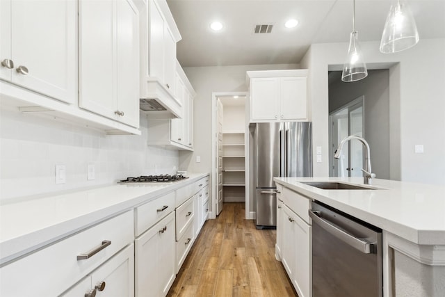 11439 Bush Clover Dr, Cypress, TX 77433 - kitchen with appliances with stainless steel finishes, a sink, light countertops, light wood-style floors, and white cabinetry