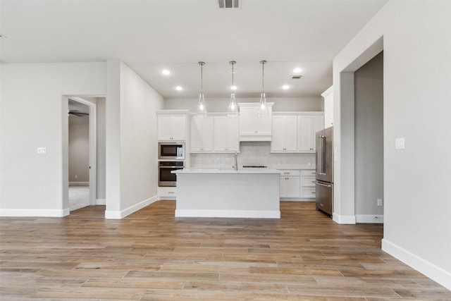 11439 Bush Clover Dr, Cypress, TX 77433 - kitchen featuring appliances with stainless steel finishes, white cabinets, light wood finished floors, tasteful backsplash, and recessed lighting