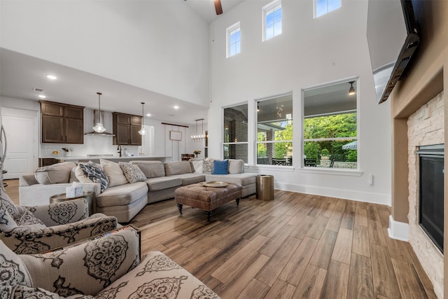 308 Lane Landing Pl, Montgomery, TX 77316 - living room with light wood-style floors, a high ceiling, a fireplace, a ceiling fan, and baseboards