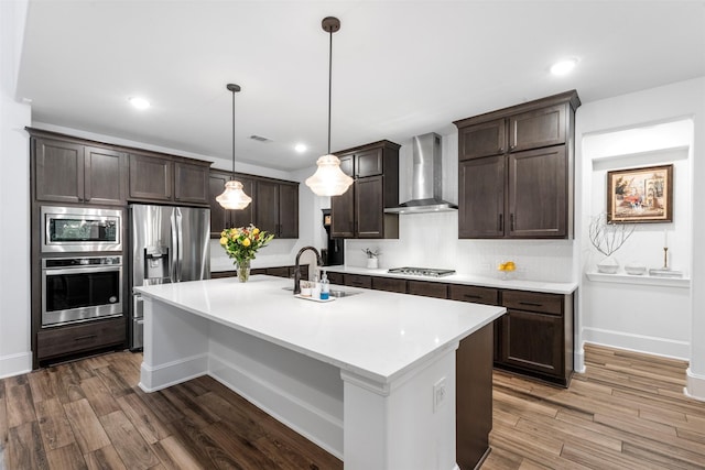 308 Lane Landing Pl, Montgomery, TX 77316 - kitchen featuring stainless steel appliances, wall chimney range hood, a sink, dark brown cabinets, and light countertops