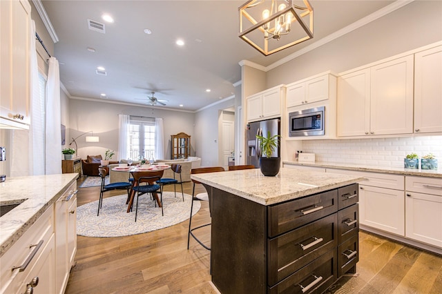 10918 Brookeshire Chase Ln, Houston, TX 77043 - kitchen with appliances with stainless steel finishes, crown molding, white cabinets, light wood-style flooring, and tasteful backsplash