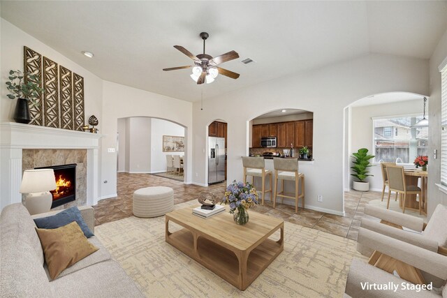 13303 Bomoseen Lake Rd, Houston, TX 77044 - living room featuring a ceiling fan, arched walkways, lofted ceiling, a tile fireplace, and baseboards