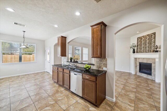 13303 Bomoseen Lake Rd, Houston, TX 77044 - kitchen featuring stainless steel dishwasher, a sink, a textured ceiling, a tiled fireplace, and arched walkways