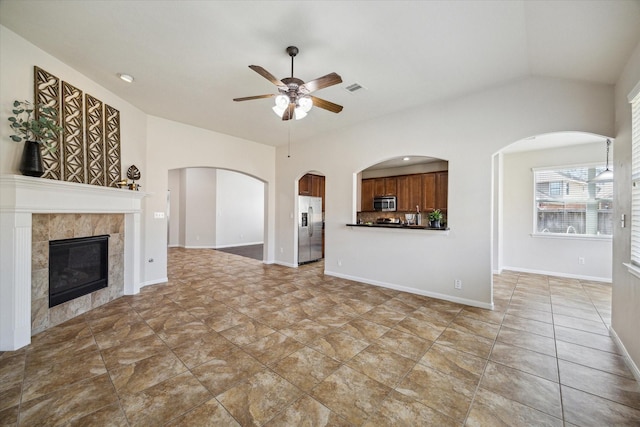 13303 Bomoseen Lake Rd, Houston, TX 77044 - unfurnished living room with ceiling fan, a tile fireplace, vaulted ceiling, arched walkways, and baseboards