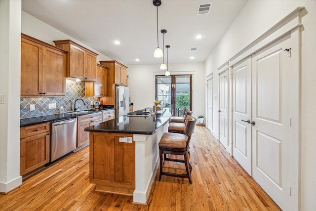6110 Clyde St, Houston, TX 77007 - kitchen featuring stainless steel appliances, light wood finished floors, a sink, brown cabinetry, and tasteful backsplash