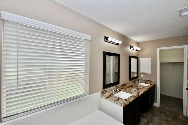 22518 Heather Way Ct, Katy, TX 77449 - full bathroom featuring double vanity, a textured ceiling, a bath, and a walk in closet