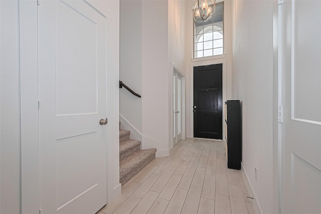 21307 Metallic Blue Dr, Cypress, TX 77433 - foyer featuring a chandelier, baseboards, stairway, light wood-style flooring, and a towering ceiling