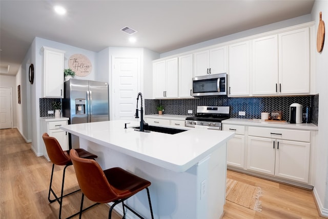 16935 Lagos Ln, Crosby, TX 77532 - kitchen with appliances with stainless steel finishes, a breakfast bar area, tasteful backsplash, a sink, and light wood-style floors